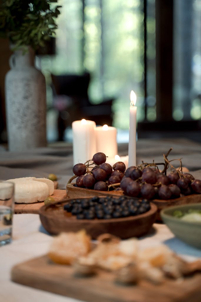 A sophisticated indoor setting with cheese, grapes, and candles for a cozy meal.