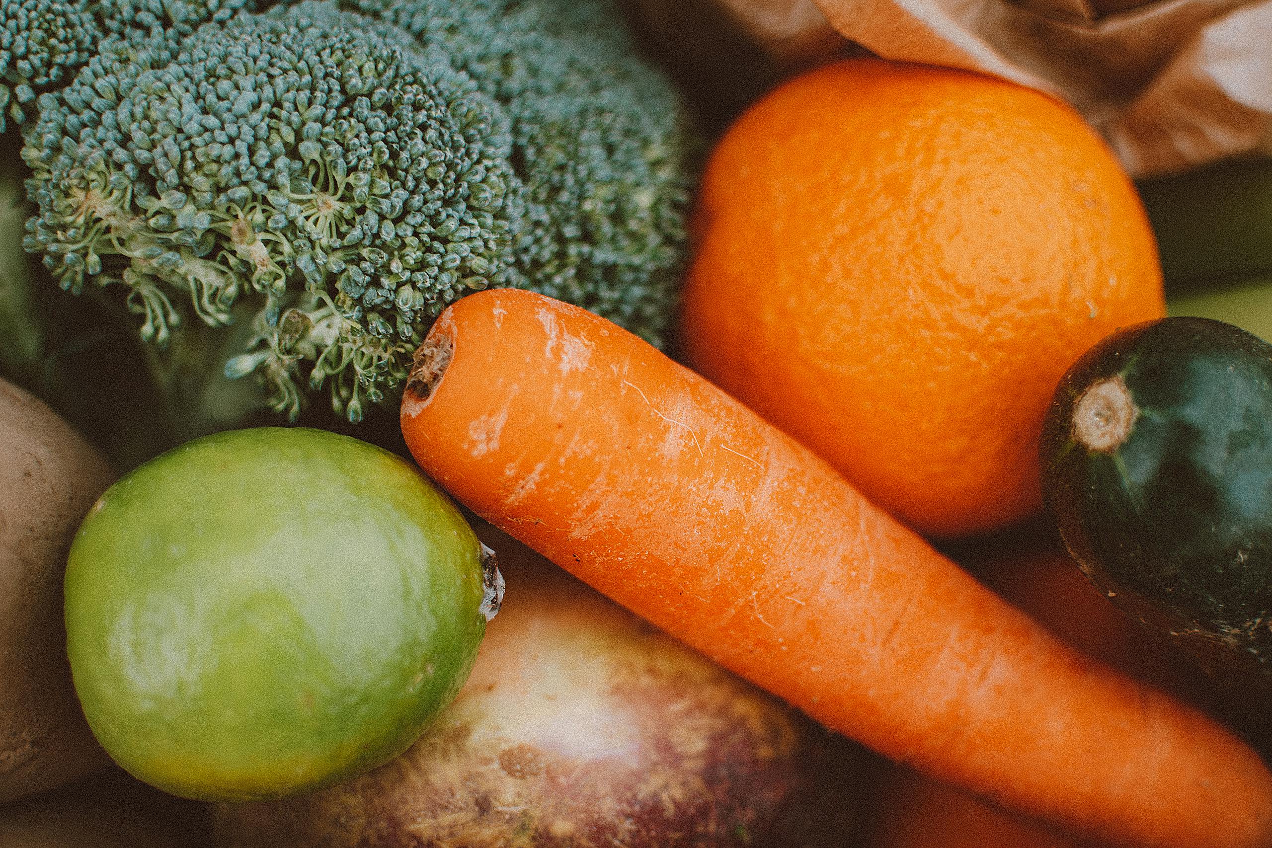 A vibrant collection of fresh vegetables and fruits including carrots, broccoli, and oranges.