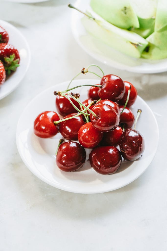 Vibrant red cherries freshly plated on a white dish, ideal for food-related imagery.