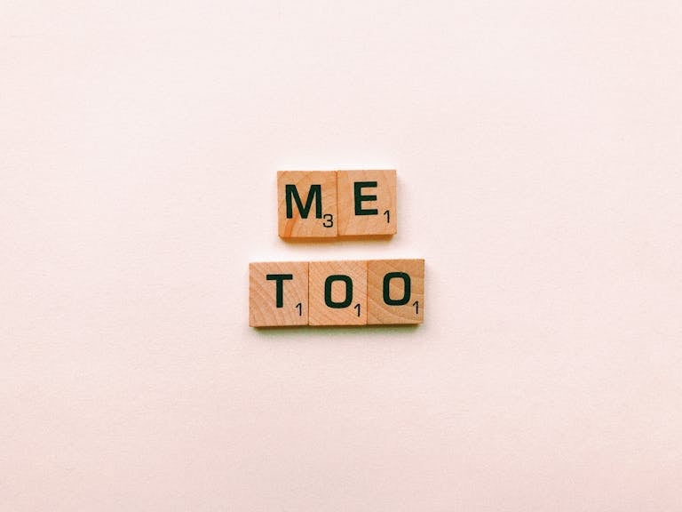 Wooden tiles spelling 'Me Too' on a plain background, symbolizing empowerment.