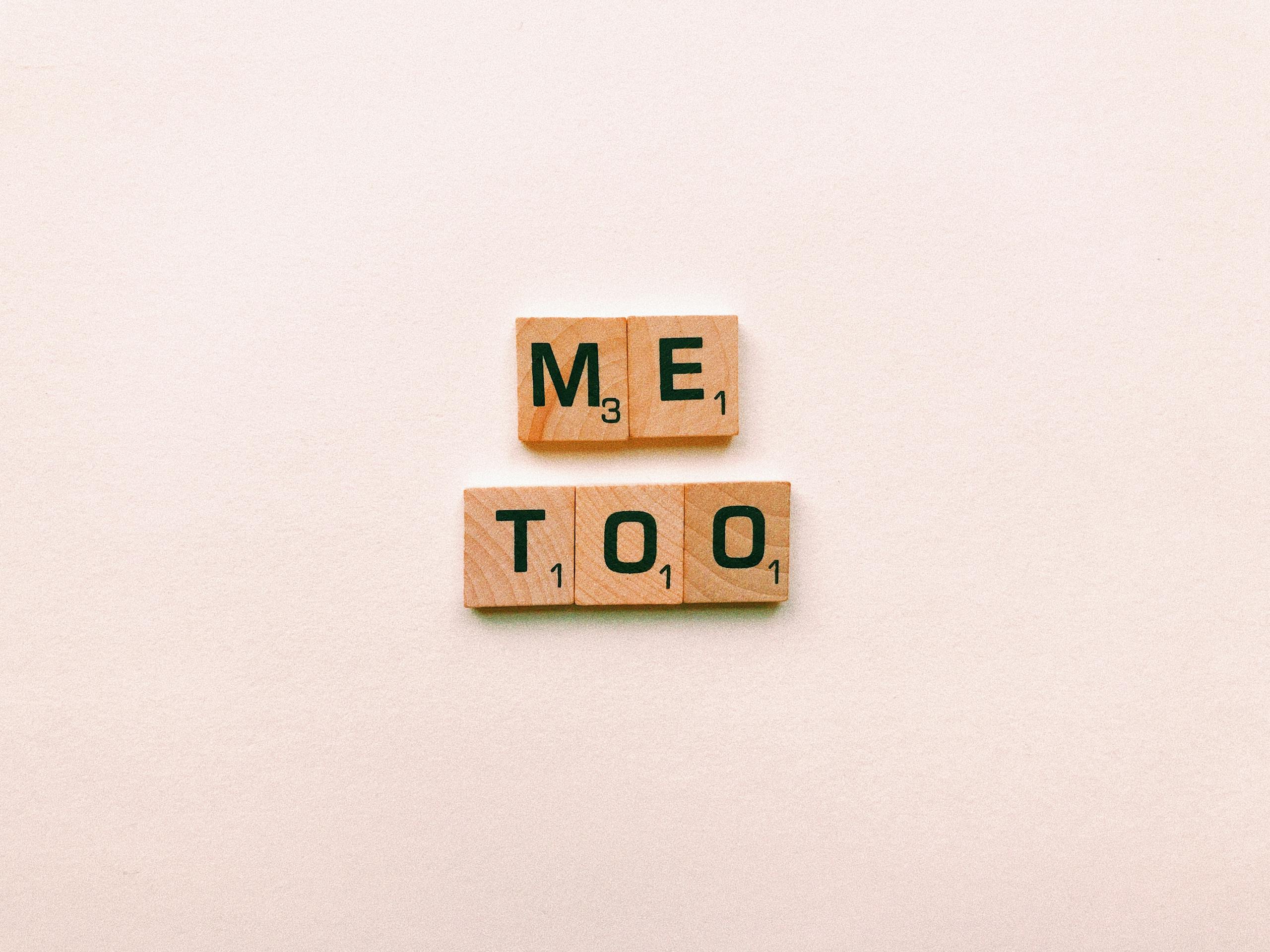 Wooden tiles spelling 'Me Too' on a plain background, symbolizing empowerment.