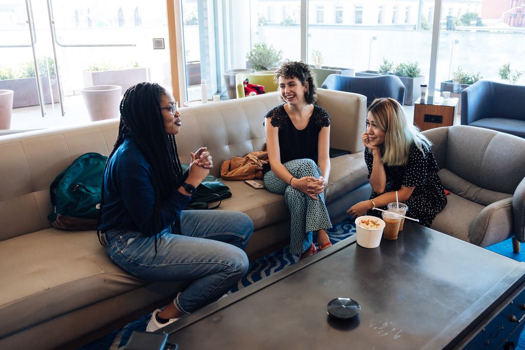 Three women chatting and enjoying drinks in a stylish indoor café setting.